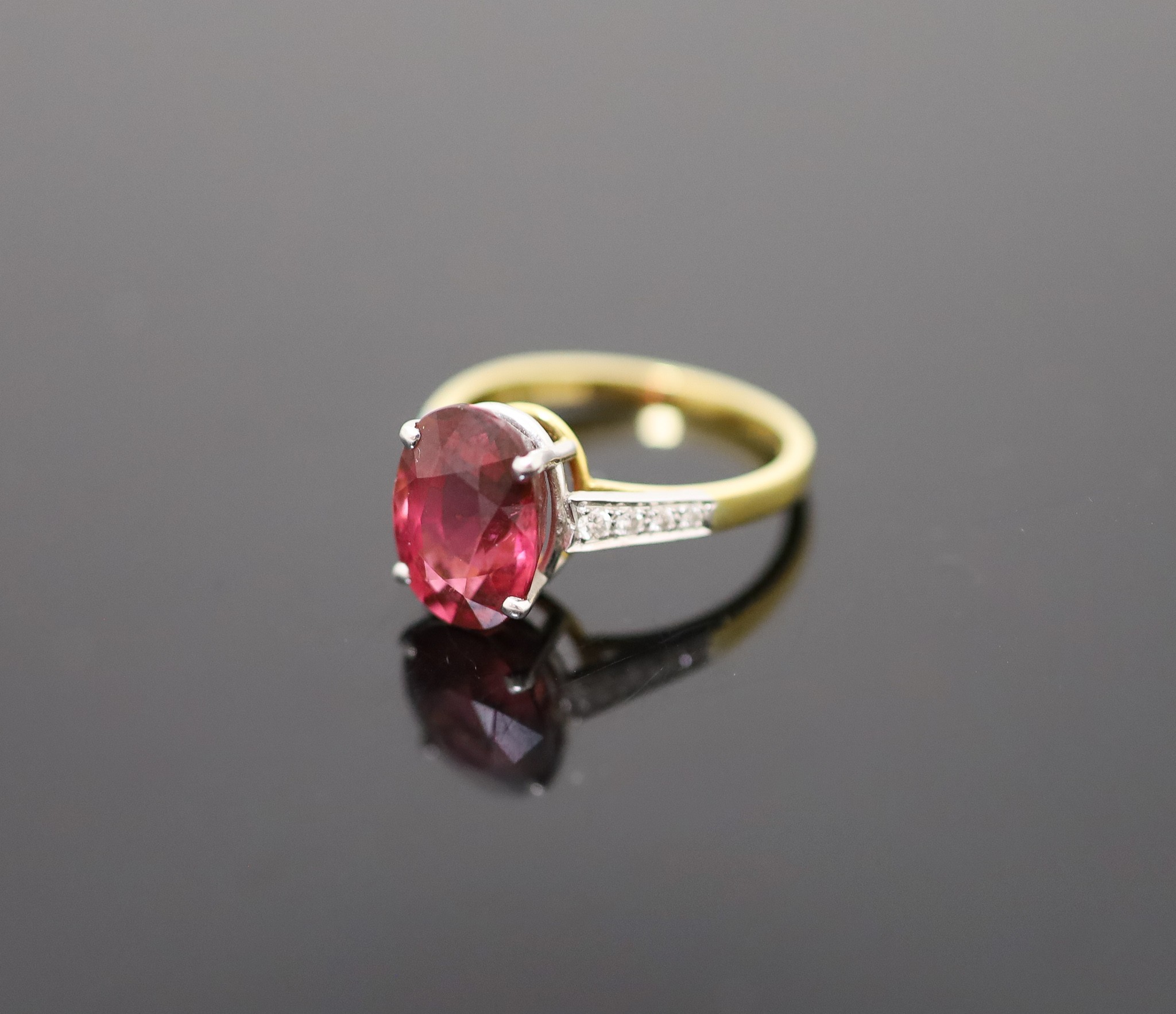 A modern 18ct gold and oval deep pink tourmaline ring, with diamond set shoulders